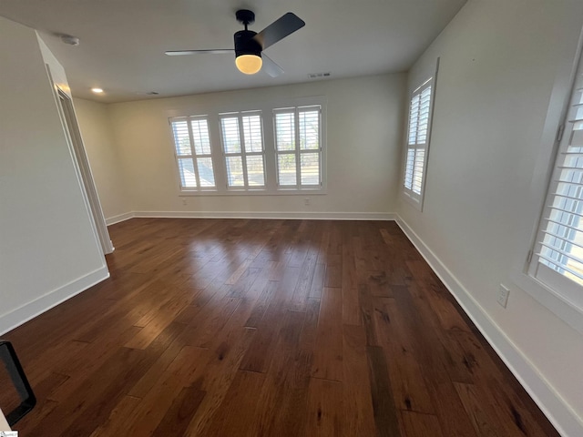 spare room with a ceiling fan, baseboards, visible vents, and dark wood-style flooring