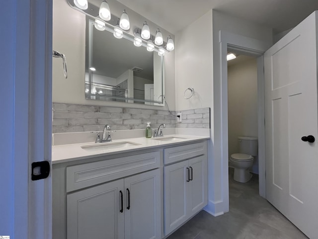 full bathroom featuring toilet, double vanity, decorative backsplash, and a sink