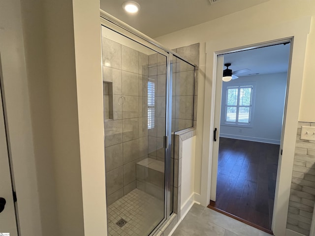 full bathroom featuring ceiling fan, a stall shower, and baseboards