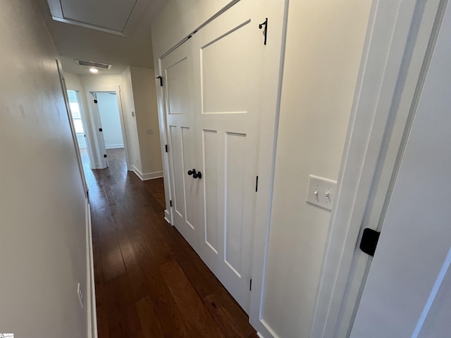 hallway with dark wood-type flooring, visible vents, and baseboards