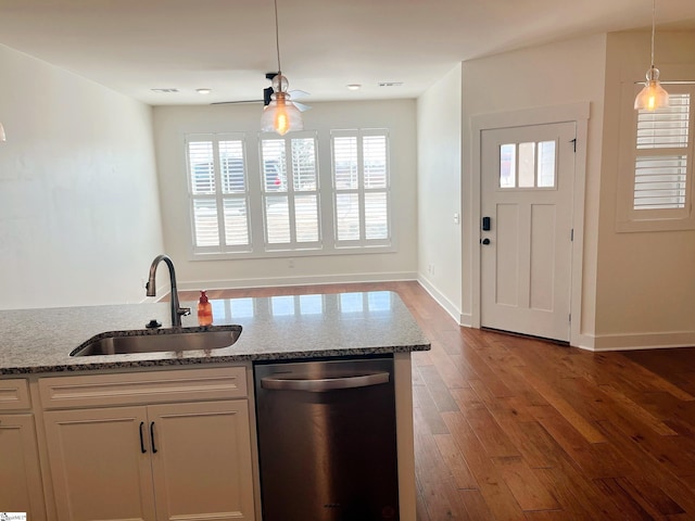 kitchen featuring stainless steel dishwasher, a sink, white cabinets, and light stone countertops