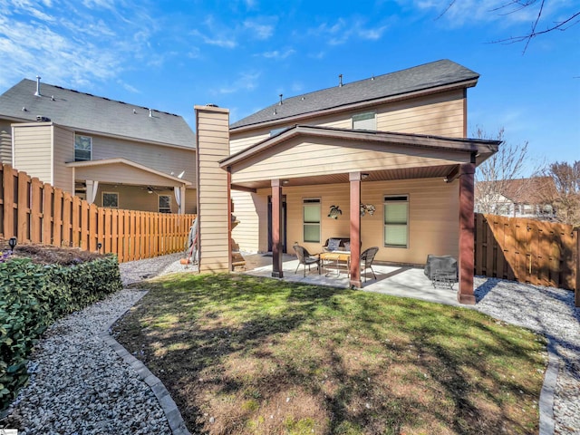 back of house featuring a chimney, a patio area, a yard, and a fenced backyard