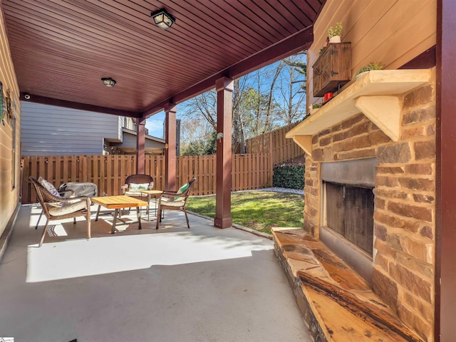 view of patio / terrace with fence and an outdoor stone fireplace