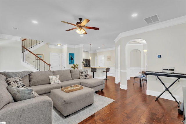 living room with visible vents, arched walkways, dark wood-style flooring, stairs, and crown molding