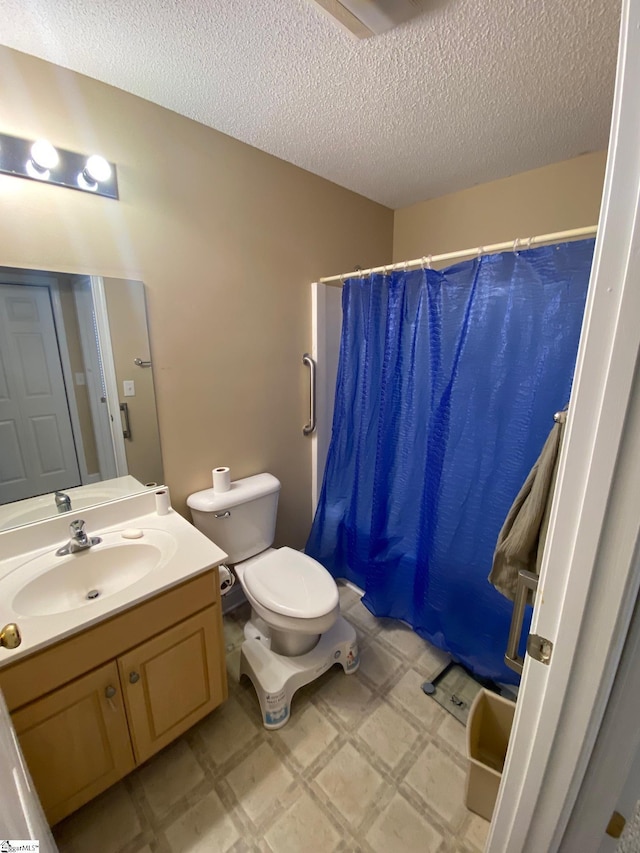 bathroom featuring toilet, vanity, a textured ceiling, and tile patterned floors