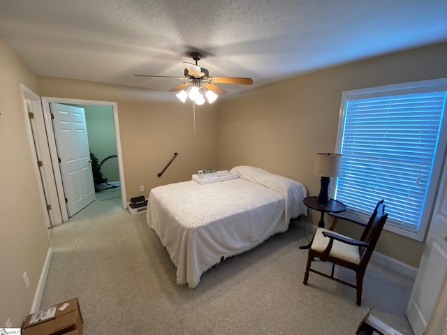 bedroom with light colored carpet, ceiling fan, a textured ceiling, and baseboards