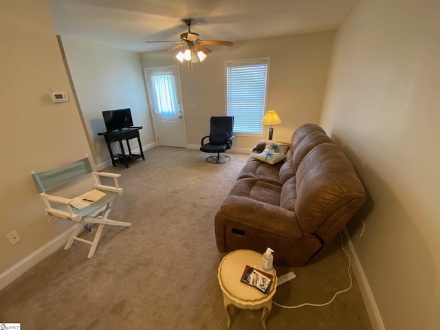 carpeted living room featuring baseboards and a ceiling fan