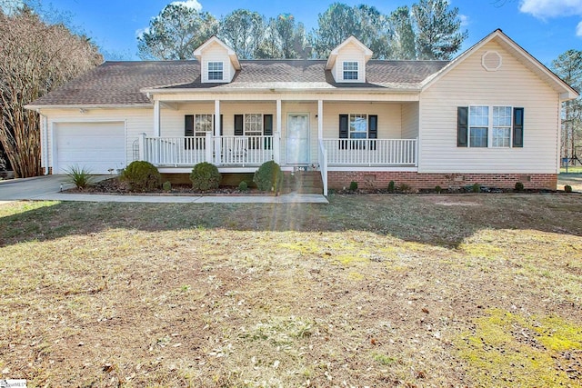 new england style home featuring covered porch, roof with shingles, an attached garage, and a front yard