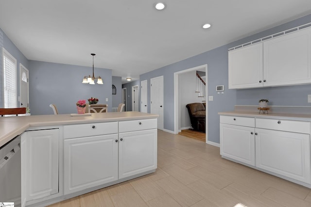 kitchen featuring decorative light fixtures, light countertops, stainless steel dishwasher, white cabinets, and a chandelier