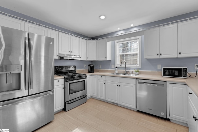 kitchen featuring stainless steel appliances, light countertops, white cabinets, a sink, and under cabinet range hood