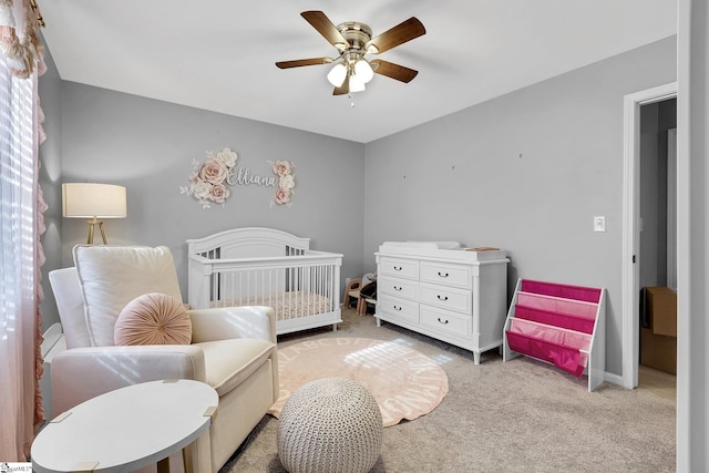 bedroom with light carpet, ceiling fan, and a nursery area