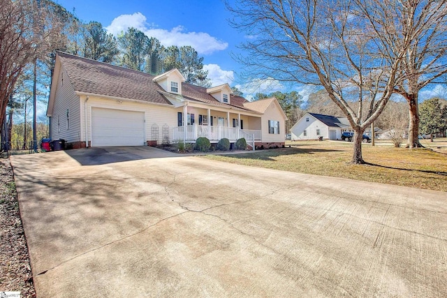 cape cod home featuring an attached garage, covered porch, a shingled roof, driveway, and a front yard