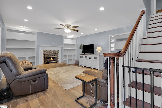 living room with light wood-style flooring, stairs, a fireplace, and recessed lighting