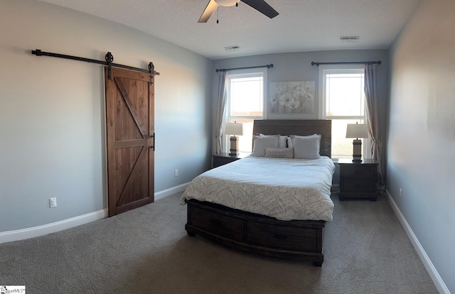 bedroom featuring a textured ceiling, a barn door, carpet flooring, visible vents, and baseboards