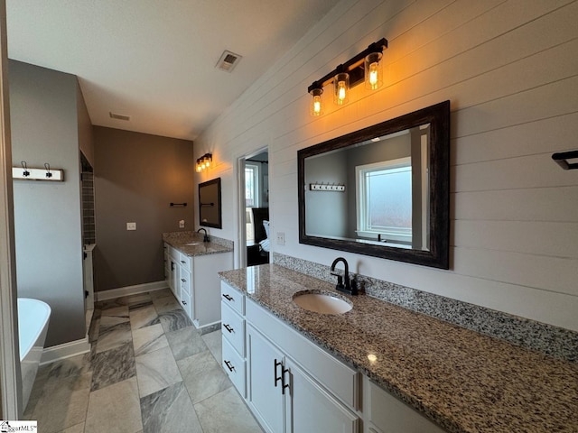 bathroom featuring a freestanding tub, wood walls, two vanities, and a sink