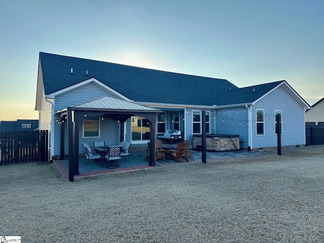 back of house featuring roof with shingles, a patio area, a jacuzzi, and fence