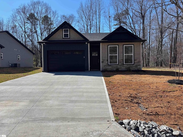 view of front of house featuring central AC unit, a garage, driveway, stone siding, and board and batten siding