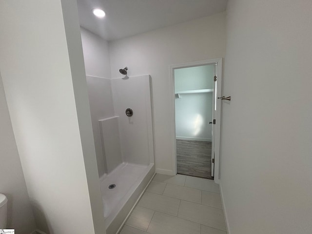 full bathroom featuring toilet, a stall shower, baseboards, and tile patterned floors