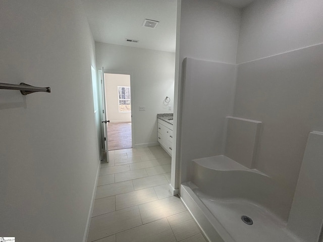 bathroom with visible vents, a shower, vanity, and baseboards