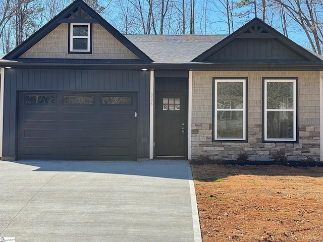 view of front of property with a garage, driveway, roof with shingles, and stone siding