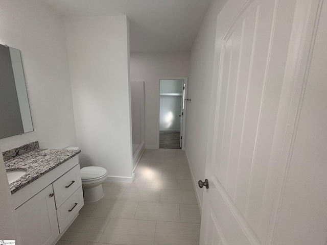 full bath featuring toilet, vanity, and baseboards