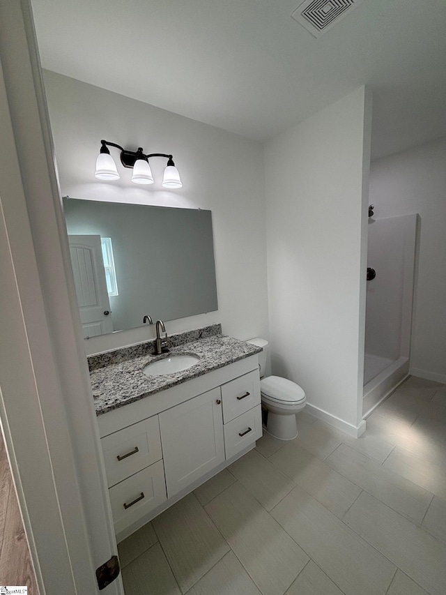 full bath with visible vents, toilet, vanity, a shower stall, and baseboards