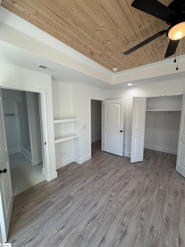 unfurnished bedroom with wooden ceiling, light wood-style flooring, visible vents, and a tray ceiling