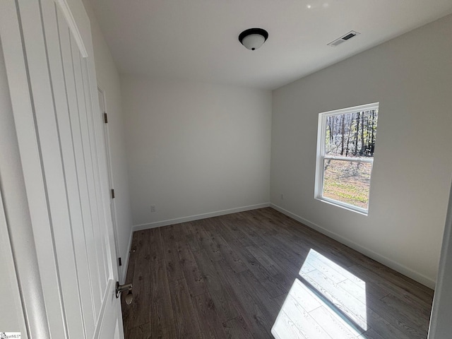 unfurnished bedroom with dark wood-style floors, visible vents, and baseboards