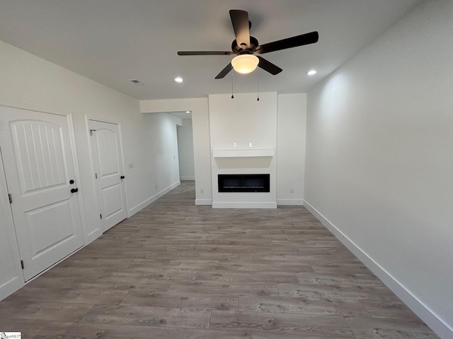 unfurnished living room with light wood-style flooring, recessed lighting, a fireplace, a ceiling fan, and baseboards