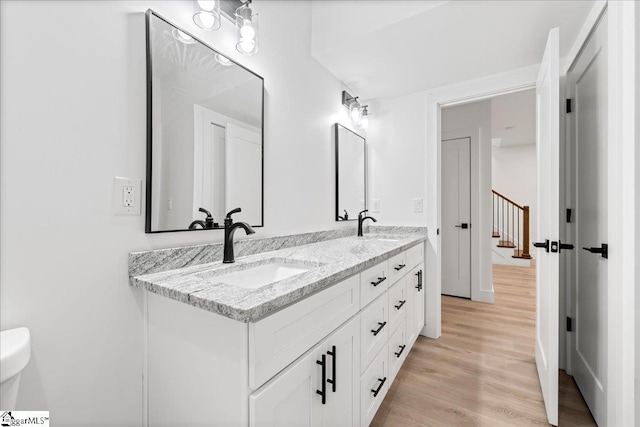 bathroom featuring wood finished floors, a sink, and double vanity