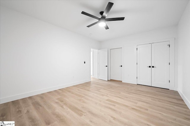 unfurnished bedroom with light wood finished floors, two closets, a ceiling fan, and baseboards