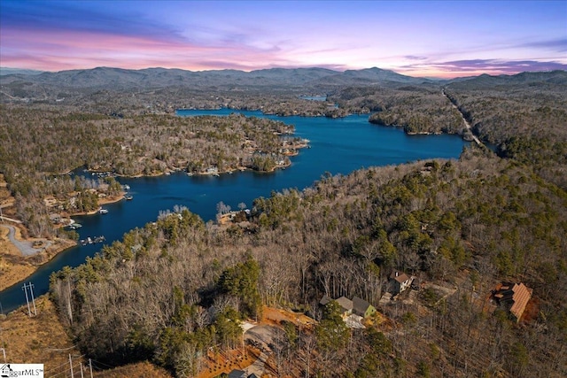 aerial view at dusk featuring a water and mountain view