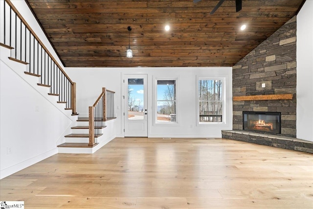 unfurnished living room featuring lofted ceiling, light wood-style floors, stairs, and a fireplace