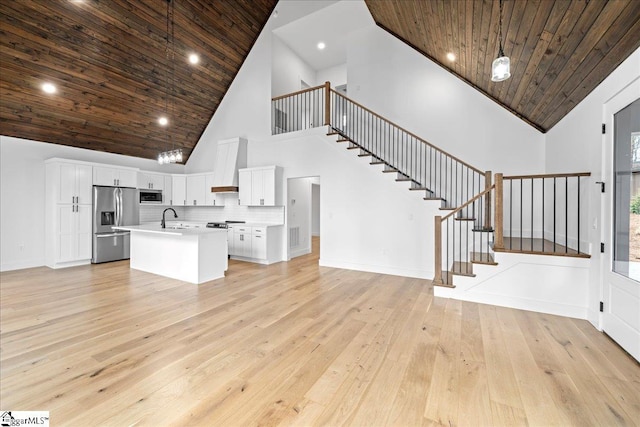 unfurnished living room with stairs, a sink, wood ceiling, and light wood-style floors