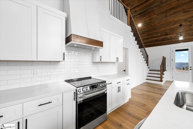 kitchen featuring wooden ceiling, backsplash, stainless steel range with electric stovetop, and white cabinets