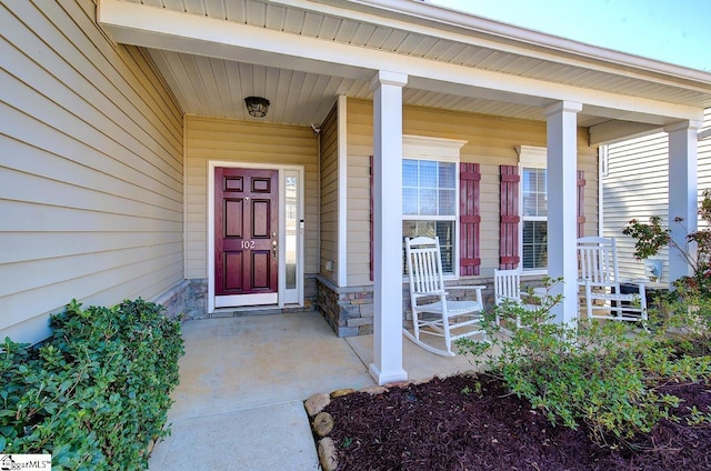 doorway to property featuring stone siding and a porch