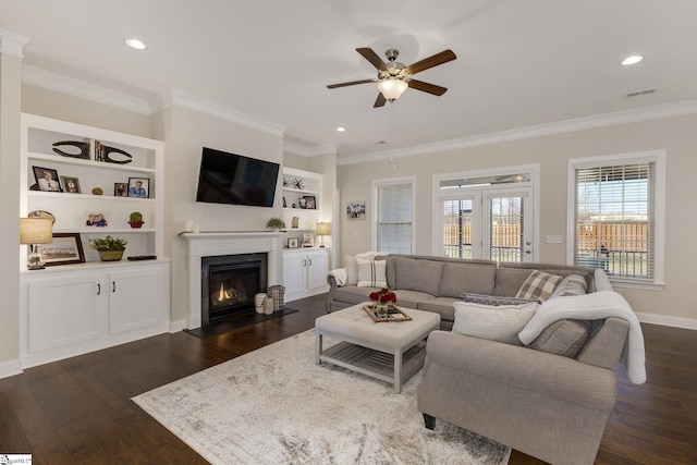 living room featuring dark wood-style floors, visible vents, crown molding, and a fireplace with flush hearth