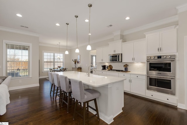 kitchen with stainless steel appliances, a sink, a kitchen breakfast bar, dark wood-style floors, and tasteful backsplash