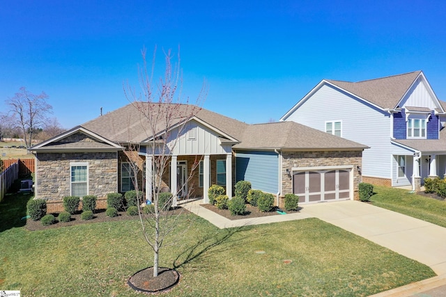 craftsman-style house featuring board and batten siding, a front yard, stone siding, and driveway