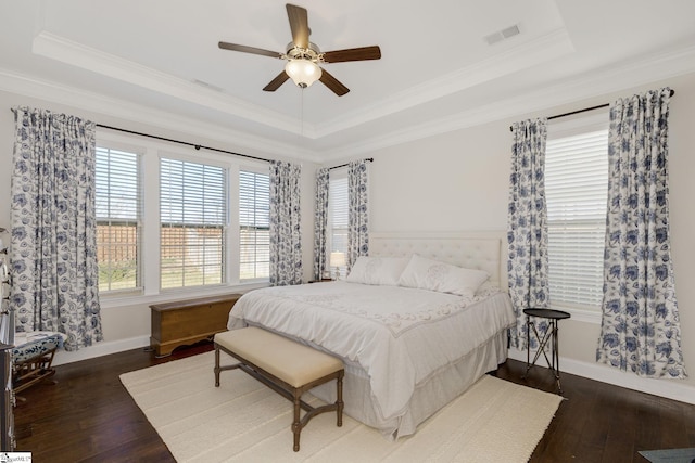 bedroom with hardwood / wood-style floors, a raised ceiling, visible vents, and crown molding