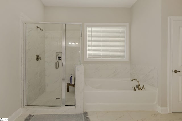 full bath featuring marble finish floor, a stall shower, a garden tub, and baseboards