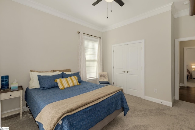 carpeted bedroom with ceiling fan, ornamental molding, a closet, and baseboards