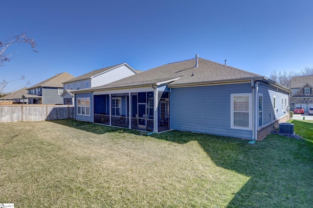 back of property with central AC unit, a lawn, fence, and a sunroom