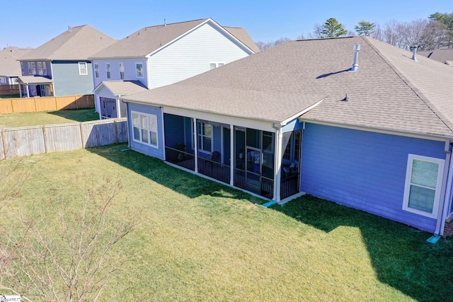 rear view of property with roof with shingles, a yard, a sunroom, fence, and a residential view