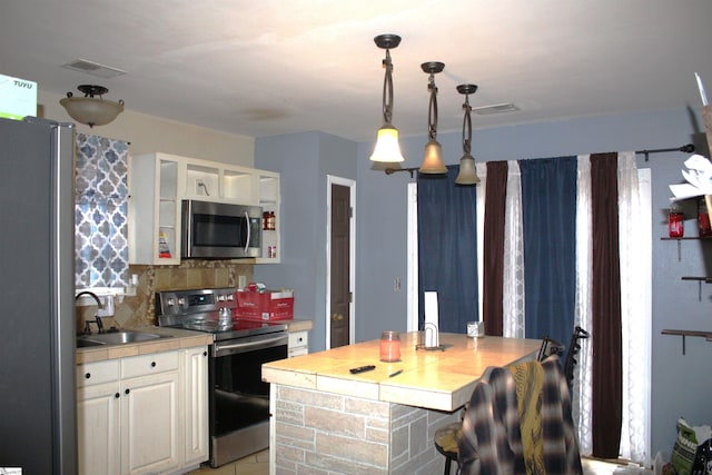 kitchen with stainless steel appliances, light countertops, glass insert cabinets, and a sink