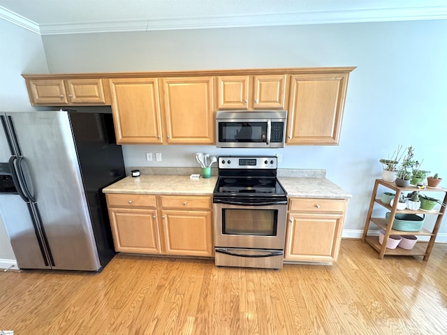 kitchen featuring baseboards, ornamental molding, stainless steel appliances, light countertops, and light wood-style floors