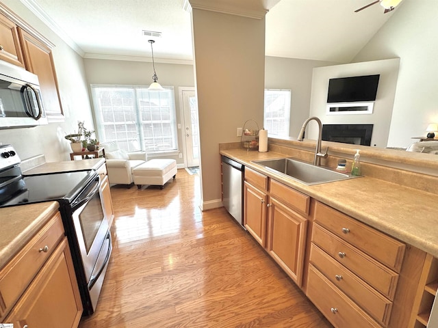 kitchen with stainless steel appliances, a sink, open floor plan, light countertops, and pendant lighting