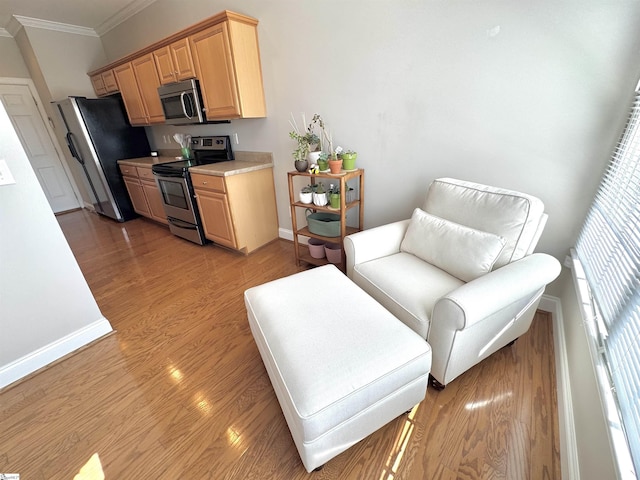 kitchen with light countertops, appliances with stainless steel finishes, light wood-style floors, ornamental molding, and baseboards