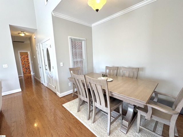 dining space featuring baseboards, wood finished floors, attic access, and crown molding