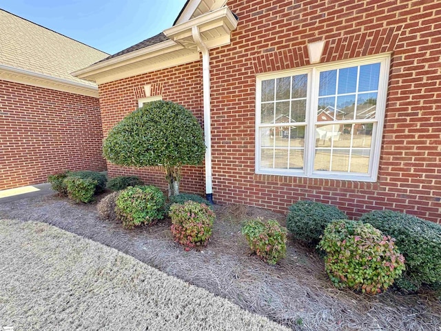 entrance to property with brick siding and roof with shingles